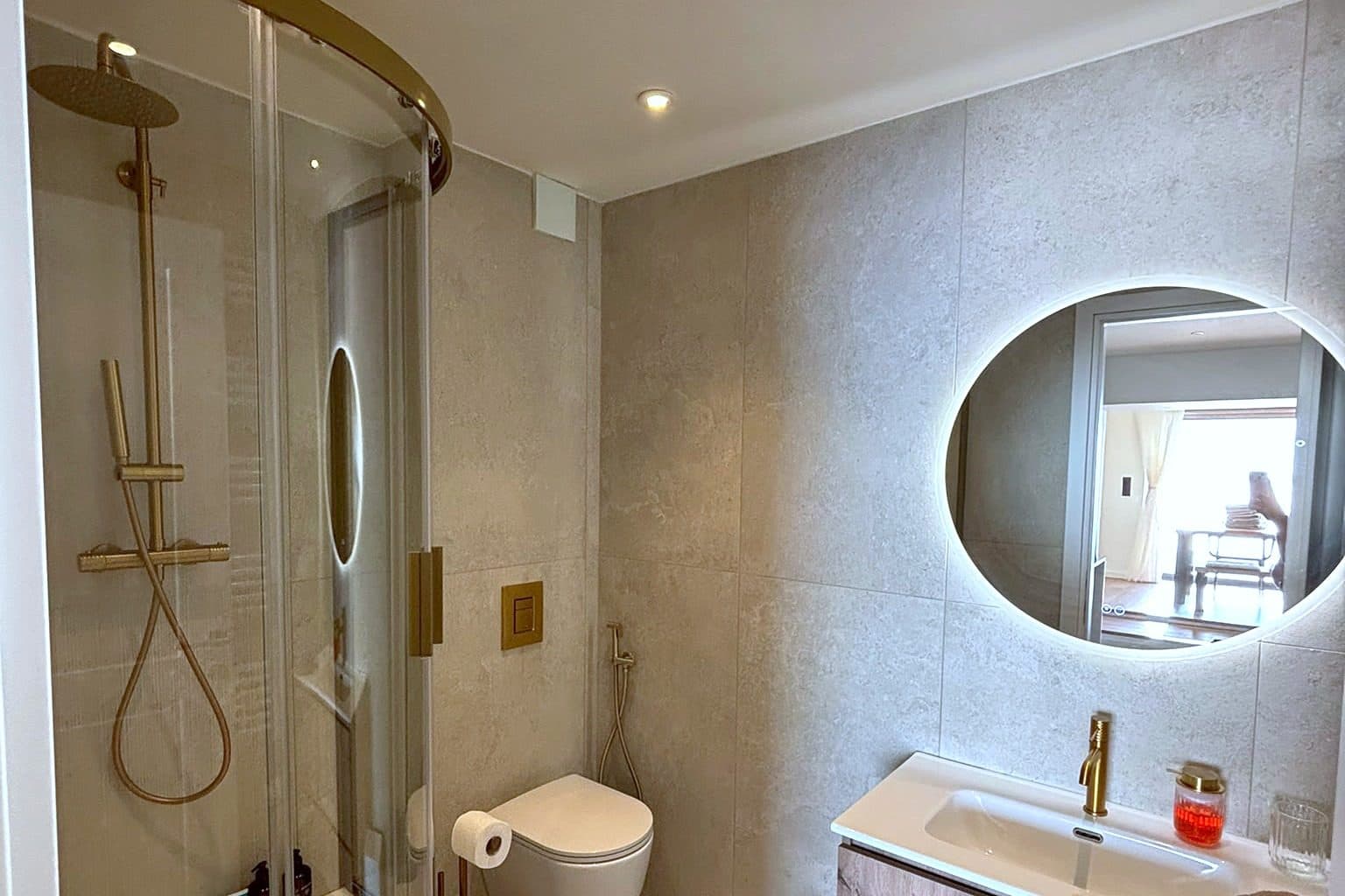 A bathroom with a round mirror above a stone vanity.